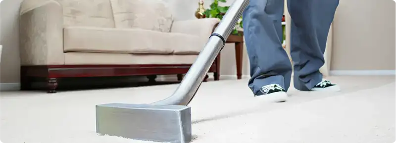 Carpet cleaning technician using a hot-water extraction wand on a light-colored carpet in a living room, Long Beach, CA.