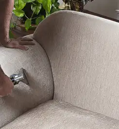 Professional upholstery cleaner deep-cleaning a fabric sofa with a handheld extraction tool and hose Long Beach, CA.